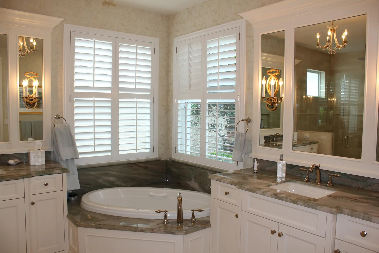 Bath with a corner soaking tub, marble surround and plantation shutters — Loxahatchee Club, Jupiter, FL