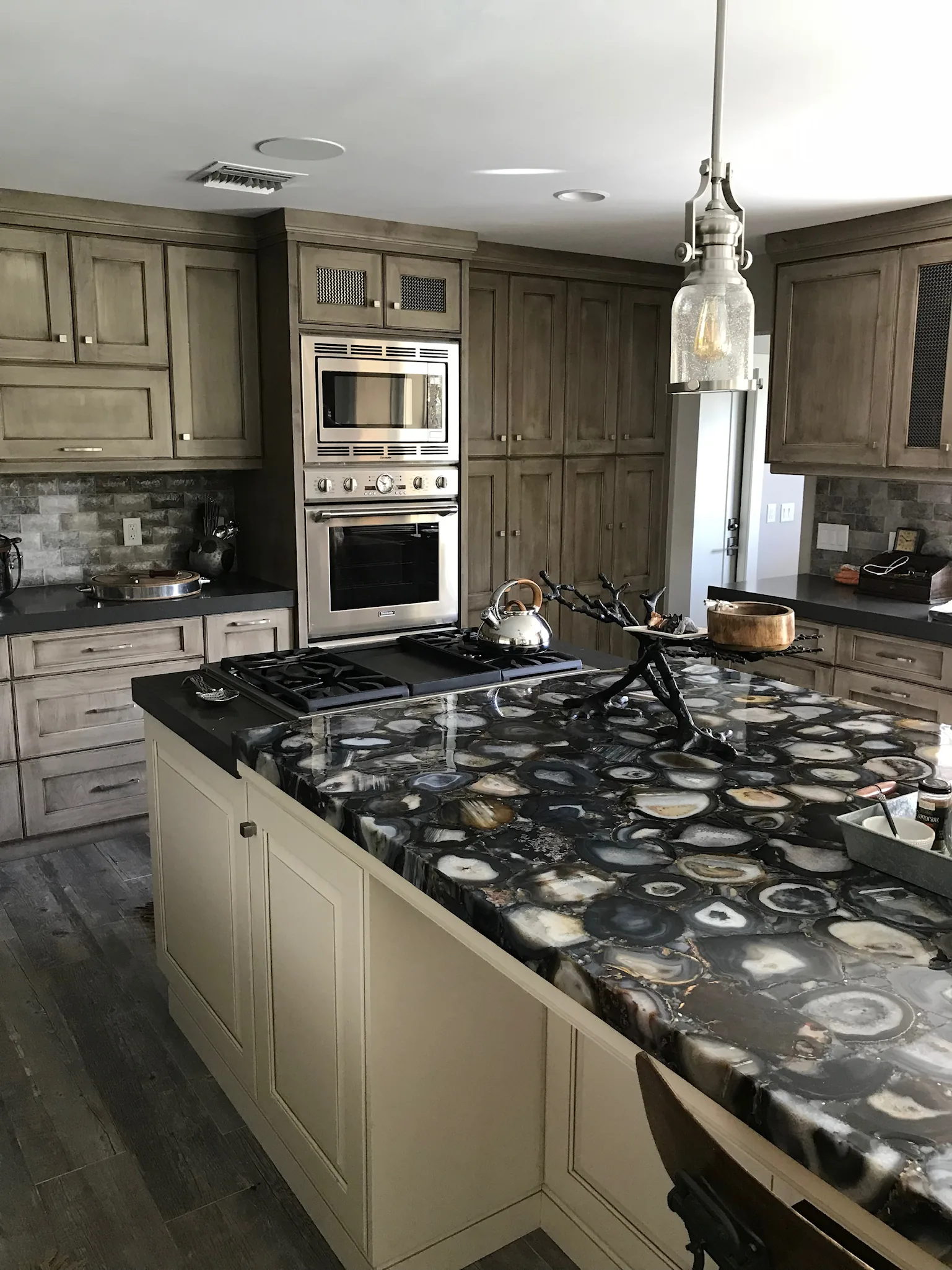 Kitchen with a granite waterfall island and gray cabinetry — Caloosa, Palm Beach Gardens, FL