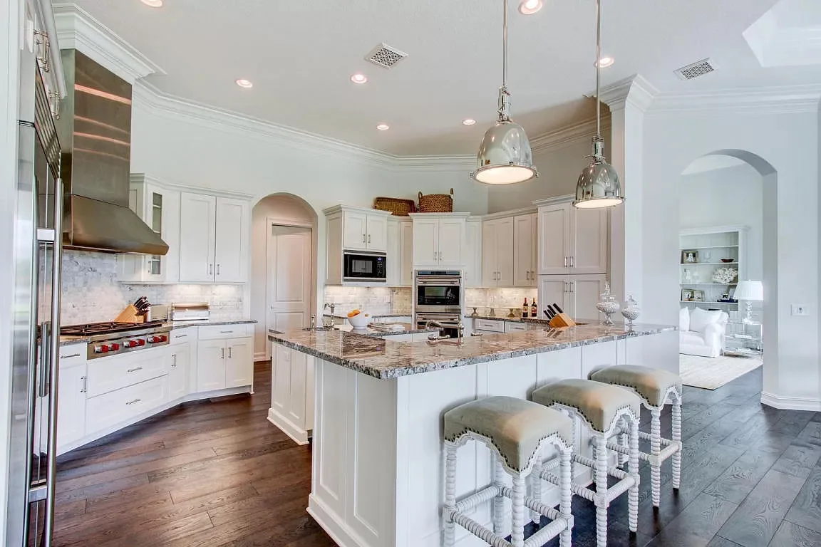 White kitchen with island seating and arched doorways — Frenchman's Harbour, North Palm Beach, FL