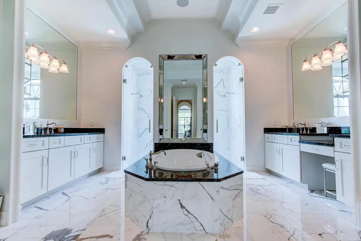 Master bath with a marble tub surround and arched mirrors — Frenchman's Harbour, North Palm Beach, FL