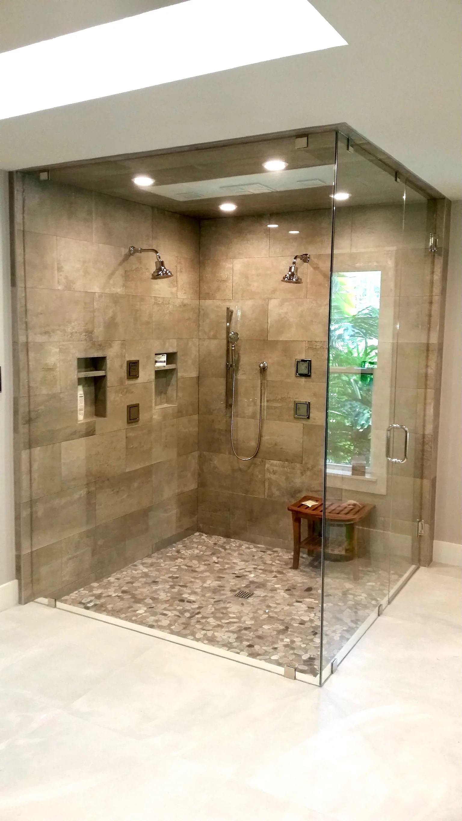 Walk-in stone shower beneath a skylight — Caloosa, Palm Beach Gardens, FL